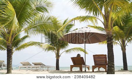 A Beautiful Girl In A Swimsuit Lies On A Lounger Under The Malmas. A Girl Is Resting By The Sea. The