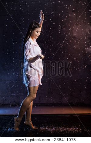 Girl In The White Shirt With Water Drops And Dark Walls Background Illuminated By Colored Light Duri