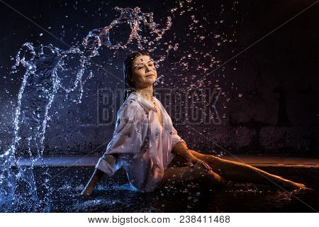 Girl In The White Shirt With Water Drops And Dark Walls Background Illuminated By Colored Light Duri