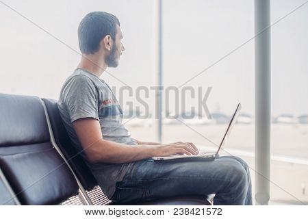Young Man Using Laptop In Airport Terminal.