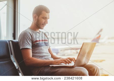 Young Man Using Laptop In Airport Terminal.