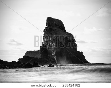 Cloudy Evening On Rocky Shore At Sunset. Sunset Mirroring In  Sea Water And Large Cracked Rocks With