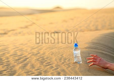 Hand Try To Catch The Bottle Of Water On Sand Desert In Hot Temperature. Concept Of To Die Of Thirst