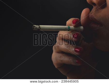 Woman With Red Nail Is Smoking Cigarette On Dark Background. Quit Smoking Concept. Bad Habit In Woma