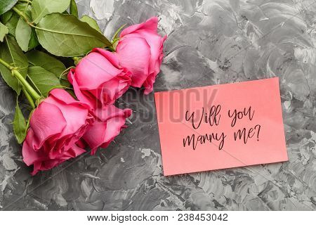 Pink Roses And A Pink Card With An Inscription, Will You Marry Me On A Gray Concrete Background. Con