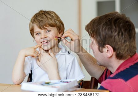 Young Dad Painting Flag On Face Of Little Son For Football Or Soccer Game. Happy Excited Preschool K