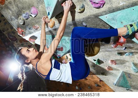 Workout Exercise. Woman Climber Climbs Indoors In Bouldering Gym. Young Woman Climbing Up On Practic
