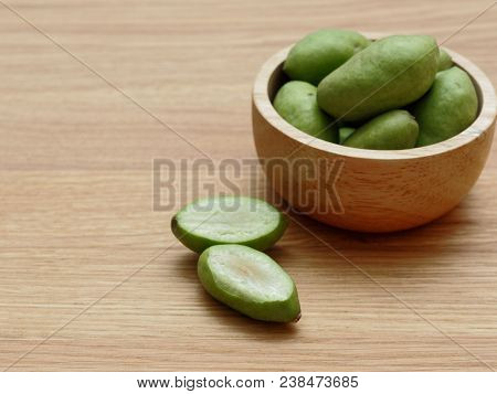 A Group Of Green Hog Plums Fruit, Which Look Like Small Mango, In Wooden Bowl Over Bright Wooden Bac