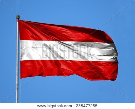 National Flag Of Austria On A Flagpole In Front Of Blue Sky.