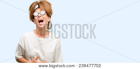 Crazy middle age woman wearing silly glasses stressful, terrified in panic, shouting exasperated and frustrated. Unpleasant gesture. Annoying work drives me crazy isolated blue background