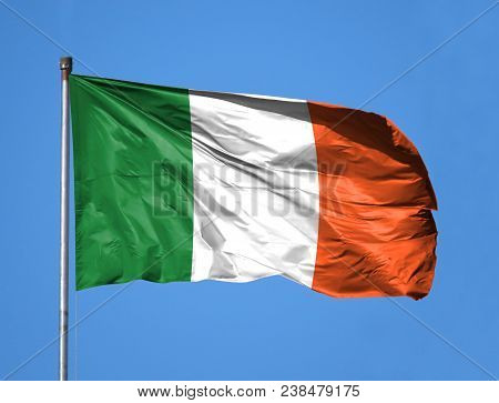 National Flag Of Ireland On A Flagpole In Front Of Blue Sky.