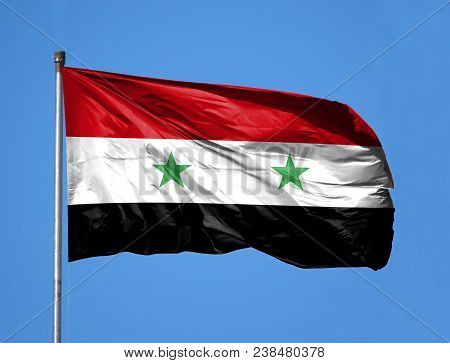 National Flag Of Syria On A Flagpole In Front Of Blue Sky.