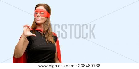Middle age super hero woman wearing red mask and cape proud, excited and arrogant, pointing with victory face isolated blue background