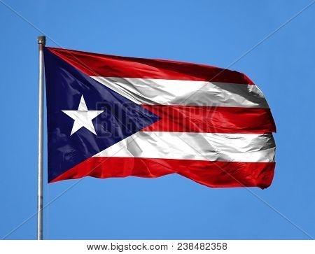 National Flag Of Puerto Rico On A Flagpole In Front Of Blue Sky.