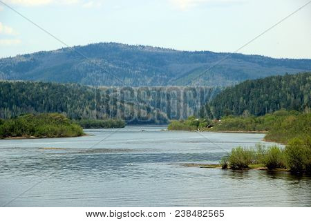 Amazing Landscape Of The Winding River And Wooden Mountain Ahead. Several Roofs And Fishermen Far Aw