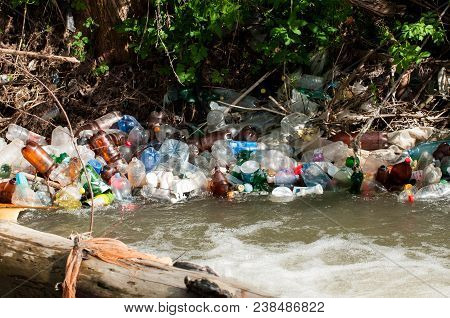 Bancu, Romania- 30 April 2018: A Bunch Of Colorful Non Degradable  Plastic Bottles In The Small Rive