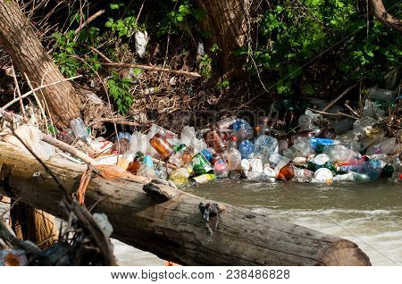 Bancu, Romania- 30 April 2018: A Bunch Of Colorful Non Degradable  Plastic Bottles In The Small Rive