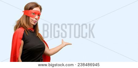 Middle age super hero woman wearing red mask and cape confident and happy with a big natural smile inviting to enter isolated blue background