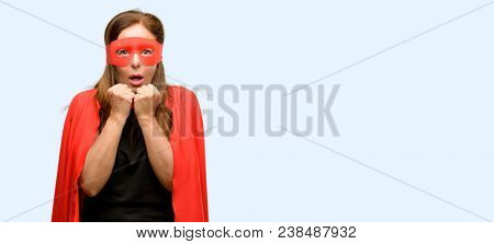 Middle age super hero woman wearing red mask and cape terrified and nervous expressing anxiety and panic gesture, overwhelmed isolated blue background