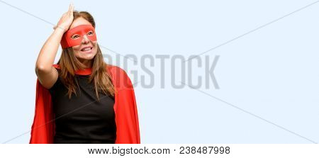 Middle age super hero woman wearing red mask and cape terrified and nervous expressing anxiety and panic gesture, overwhelmed isolated blue background