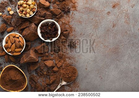 Dark Broken Chocolate Pieces On Dark Background, Cocoa Powder And Various Nuts In Bowls Closeup. Swe