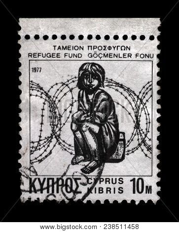 NICOSIA, CYPRUS - CIRCA 1977: canceled stamp printed in Cyprus shows refugee child and barbed wire, circa 1977. Vintage stamp isolated on black background.