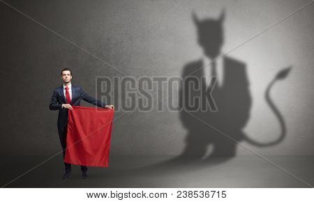 Businessman standing with red cloth in his hand and devil shadow on the background