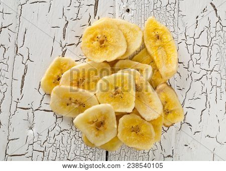Heap Of Dried Banana Chips Snack On White Rustic Table Top View