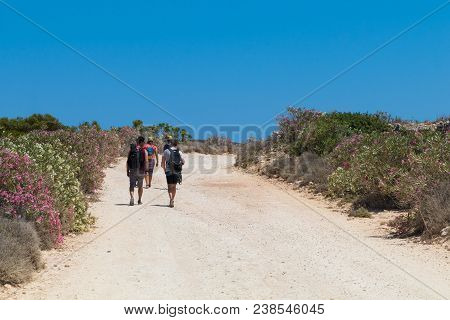 Young Tourists Walking Along The Path To St. Maria Bay And Beach, Through The Wild Countryside Of Co