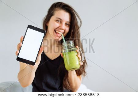 Young Pretty Woman Portrait Drink Smoothie And Show Shite Screen In Smartphone. White Background. Co