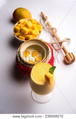 Mango Lassi Or Smoothie In Big Glass Or Small Bottles With Curd, Cut Fruit Pieces And Blender. Moody