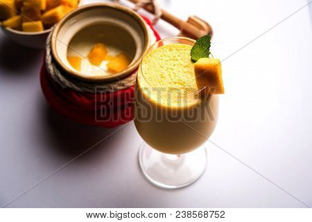 Mango Lassi Or Smoothie In Big Glass Or Small Bottles With Curd, Cut Fruit Pieces And Blender. Moody