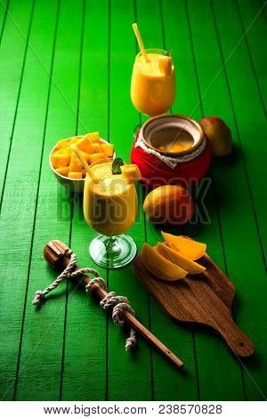 Mango Lassi Or Smoothie In Big Glass Or Small Bottles With Curd, Cut Fruit Pieces And Blender. Moody