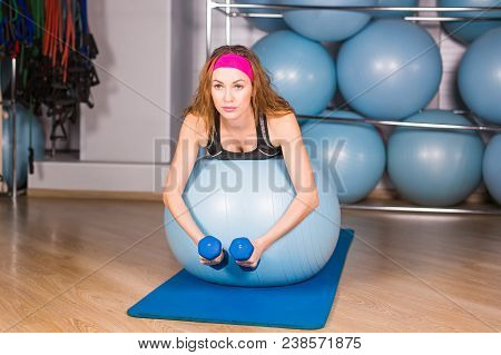Woman Exercising With Dumbbells On A Fitness Ball.