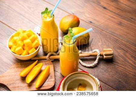Mango Lassi Or Smoothie In Big Glass Or Small Bottles With Curd, Cut Fruit Pieces And Blender. Moody