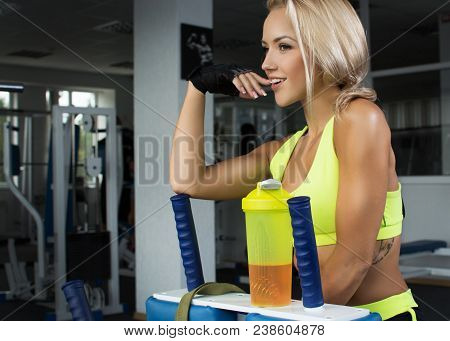 Active Sexy Blonde Woman In Sportswear Sitting On Sport Equipment. Gym. Sports Nutrition. Amino Acid