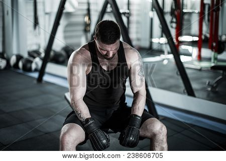 Tired Male Boxer Sitting On Stool In Gym