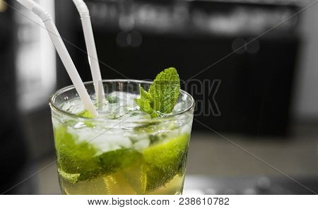Closeup Glass Of Unalcohol Mohito Cocktail With Lime And Mint And With A Two Tubes At Bar Background