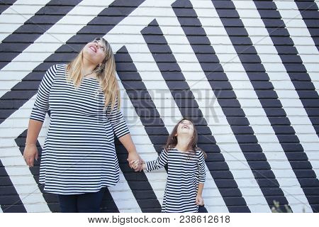 Mom Holding Her Daughter Hands On A Street Art Wall