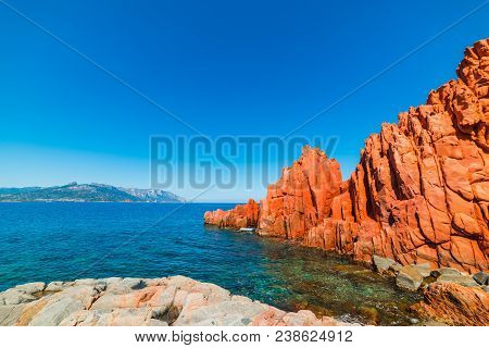 Red Rocks And Blue Sea In Rocce Rosse Beach. Sardinia, Italy