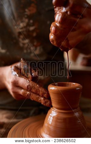 Close-up Hands Of A Male Potter In Plaid Shirt And Dirty Apron Who Molds A Vase From Clay, Selective