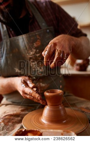 Close-up Hands Of A Male Potter In Plaid Shirt And Dirty Apron Who Molds A Vase From Clay, Selective