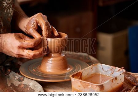 Close-up Hands Of A Male Potter In Plaid Shirt And Dirty Apron Who Molds Bowl From Clay, Selective F