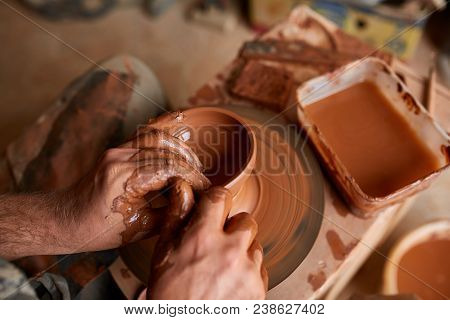 Close-up Hands Of A Male Potter In Plaid Shirt And Dirty Apron Who Molds Bowl From Clay, Selective F