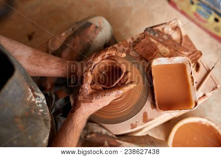 Close-up Hands Of A Male Potter In Plaid Shirt And Dirty Apron Who Molds Bowl From Clay, Selective F
