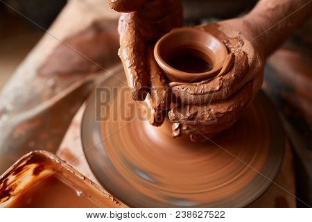 Close-up Hands Of A Male Potter In Plaid Shirt And Dirty Apron Who Molds Bowl From Clay, Selective F