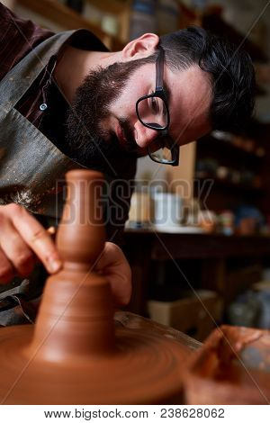 Portrait Of A Handsome Bearded Male Potter In Plaid Shirt And Dirty Apron Who Molds Bowl From Clay, 