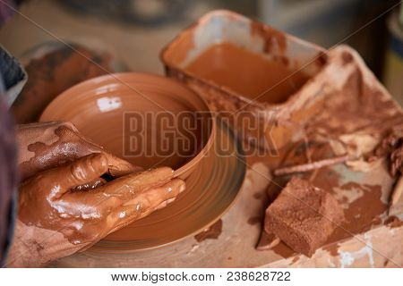 Close-up Hands Of A Male Potter In Plaid Shirt And Dirty Apron Who Molds Bowl From Clay, Selective F
