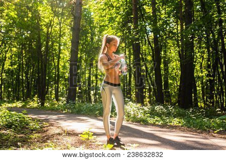 Young Woman Drinking Water After Running Outdoors.