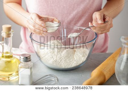 Women Adds The Baking Powder Into The Glass Bowl With Flour. Step By Step Recipe Of Homemade Mexican